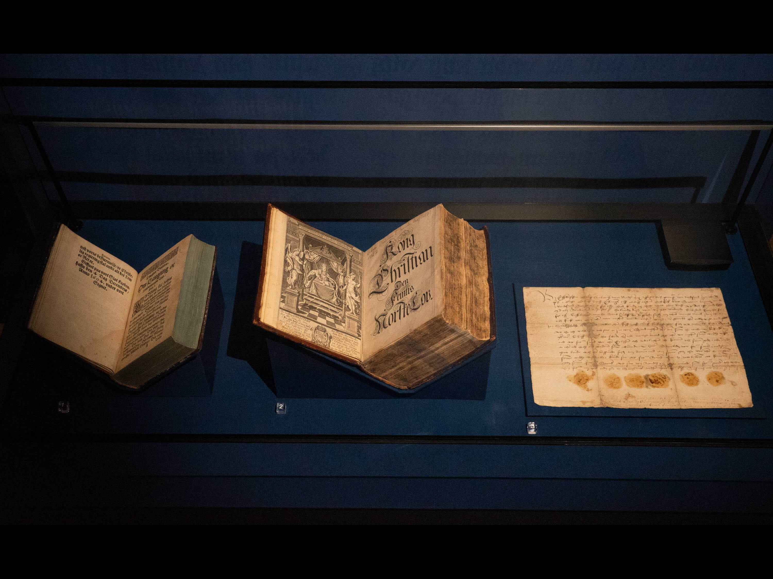 The first printed version of the Laws of the Land, Christian V's Norske Lov. and one of the oldest charters on paper - from a showcase in the exhibition.